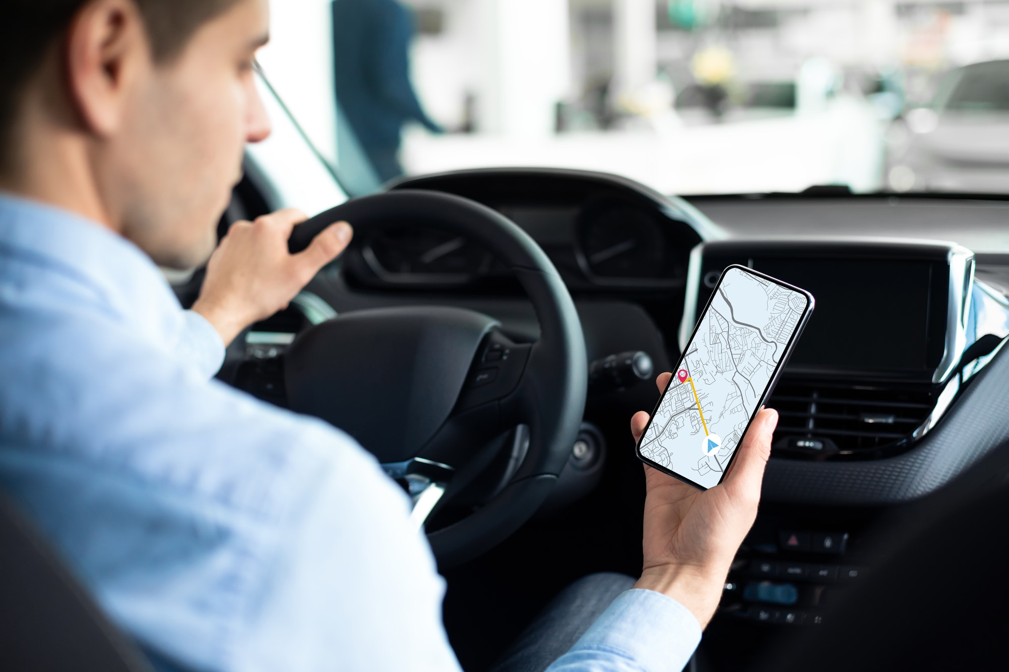 Young Man Using GPS Service Navigation App On Smartphone While Driving Car